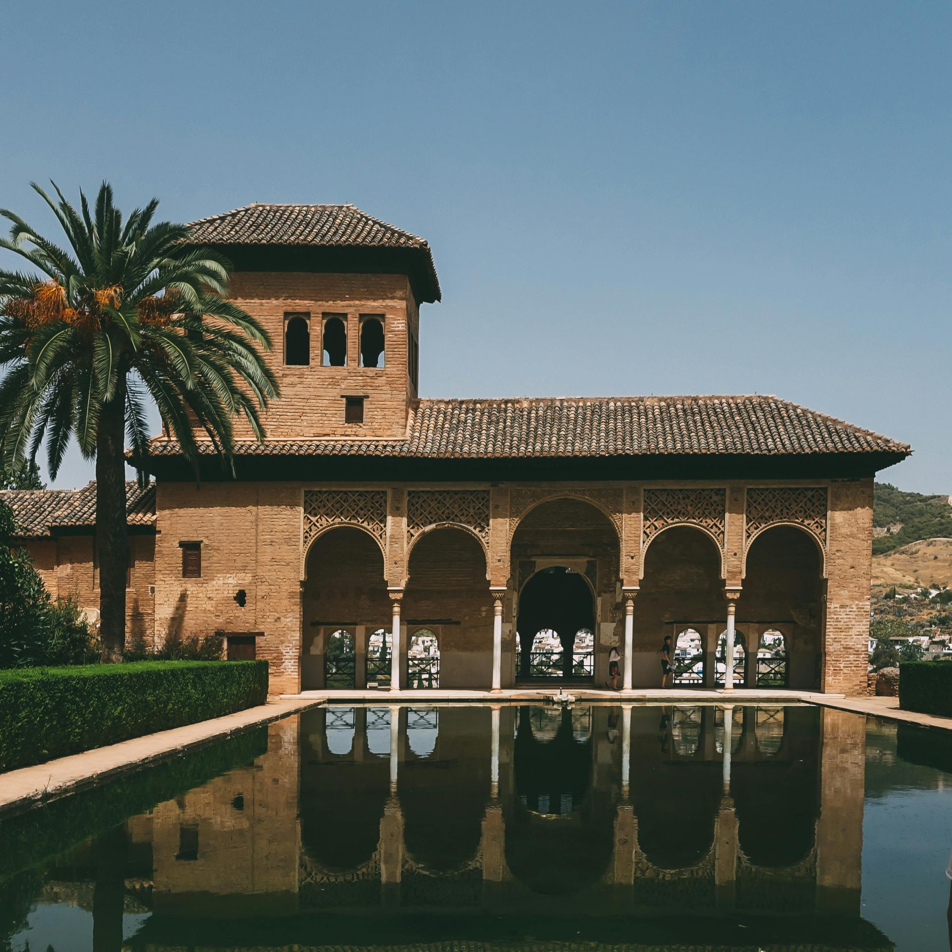 Capture of Alhambra's arches and reflection in Granada, Spain, under clear daylight.