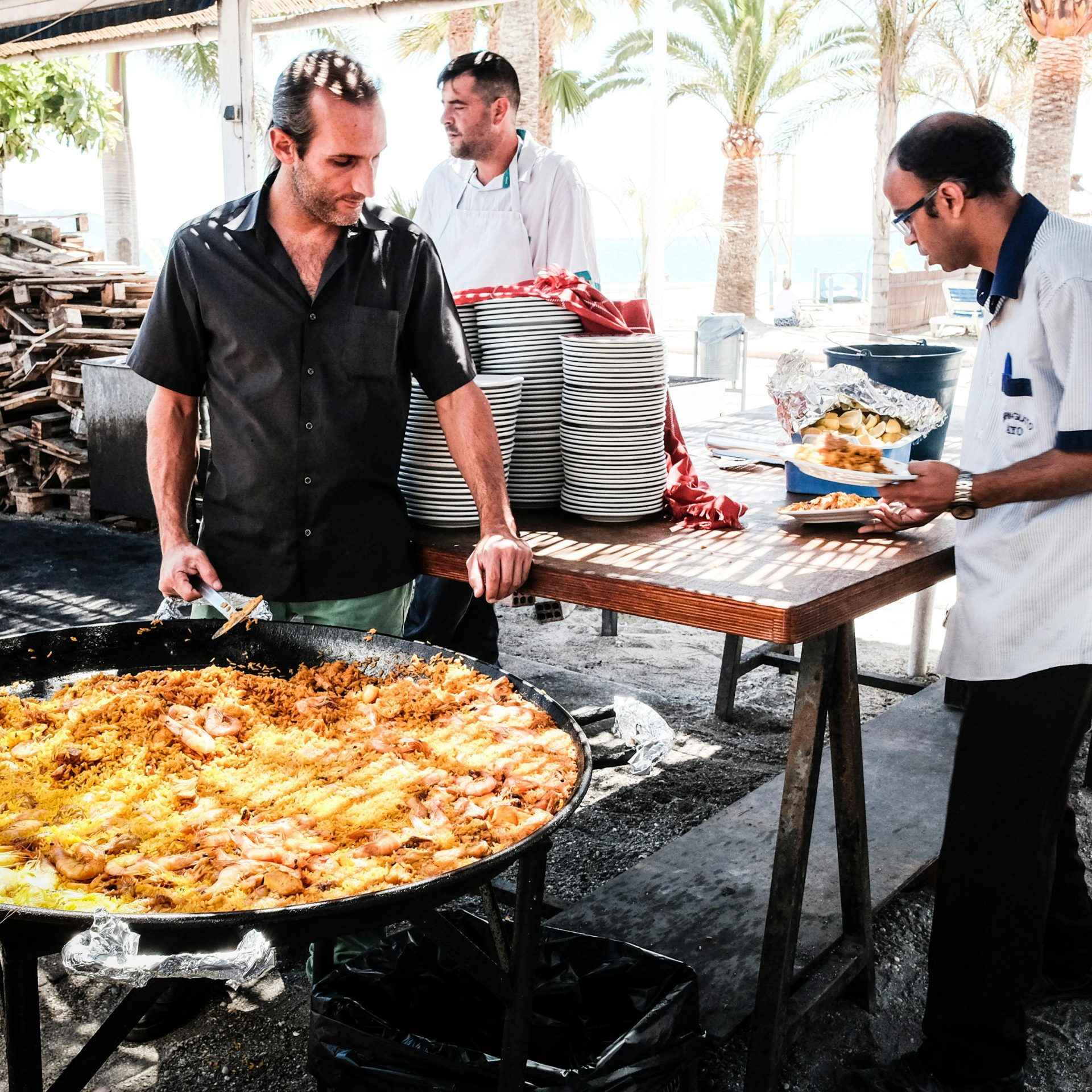 Men preparing delicious paella at a seaside restaurant in Nerja, Spain.