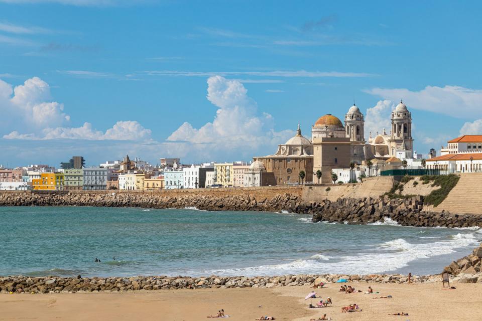 a beach with buildings and a body of water in the background